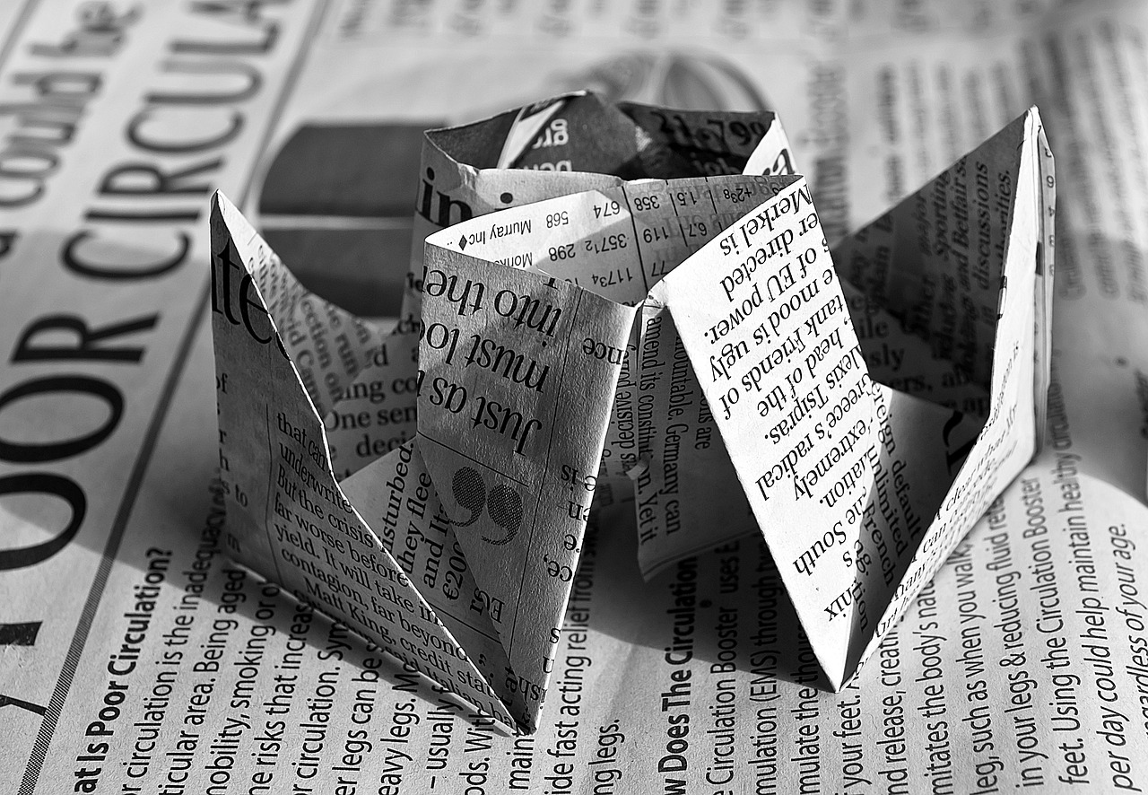 a folded up piece of paper sitting on top of a newspaper, by Matija Jama, pixabay, fine art, dodecahedron, ships, b&w!, papier - mache