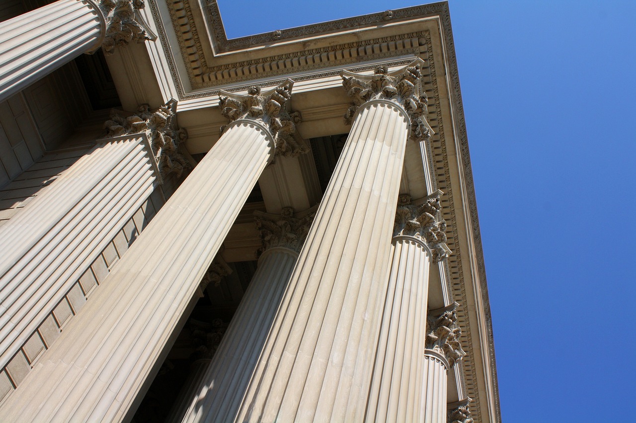 a tall building with a clock on top of it, flickr, neoclassicism, classical stone columns, court session images, view from bottom to top, sunlit