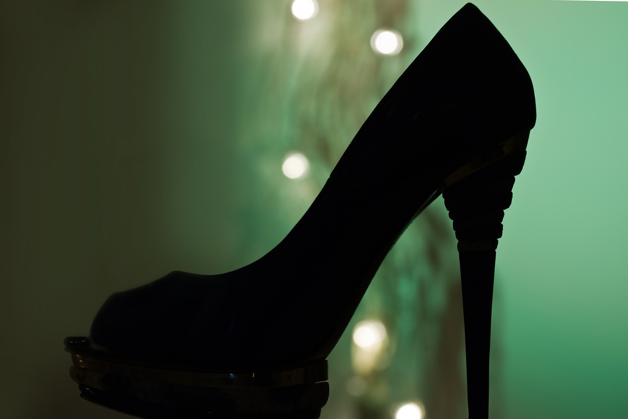 a black high heeled shoe sitting on top of a table, a picture, by Maksimilijan Vanka, pixabay, hurufiyya, dazzling lights, simple detail. greenish lighting, holiday season, seduction