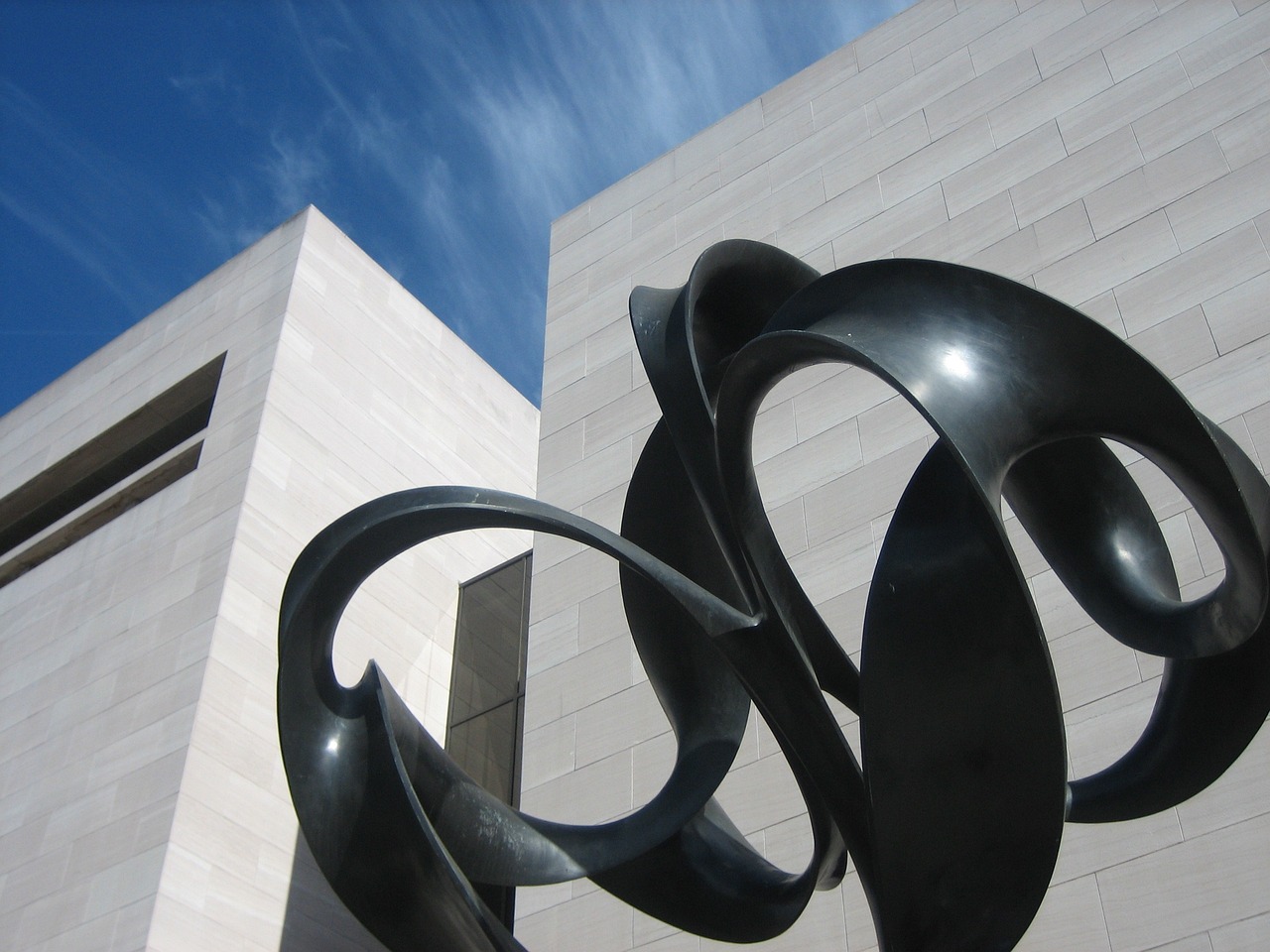 a sculpture in front of a building with a blue sky in the background, an abstract sculpture, by Alexander Stirling Calder, flickr, smithsonian american art museum, tendrils in the background, ultrafine detail ”, award-winning details”