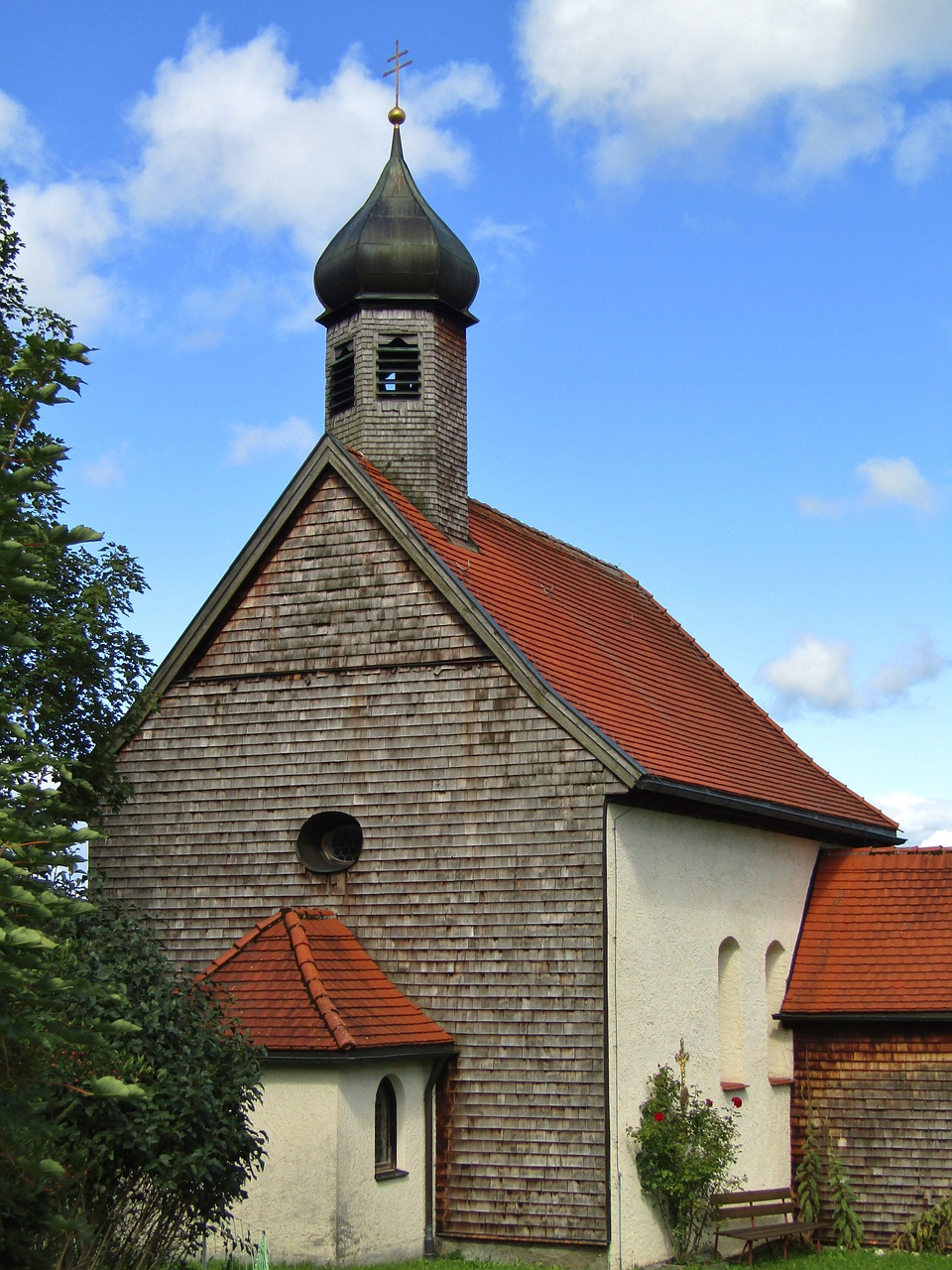 a church with a steeple and a bell tower, a photo, by Karl Pümpin, orange roof, side - view, style of vogelsang, well preserved