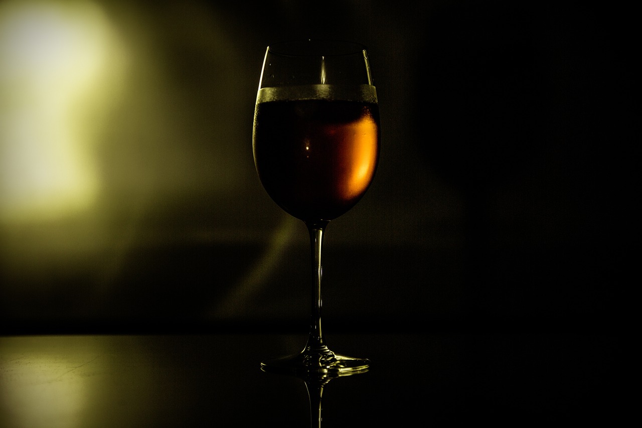 a glass of wine sitting on top of a table, by Jan Rustem, high contrast backlight, shot at dark with studio lights, blog-photo, reflecting light