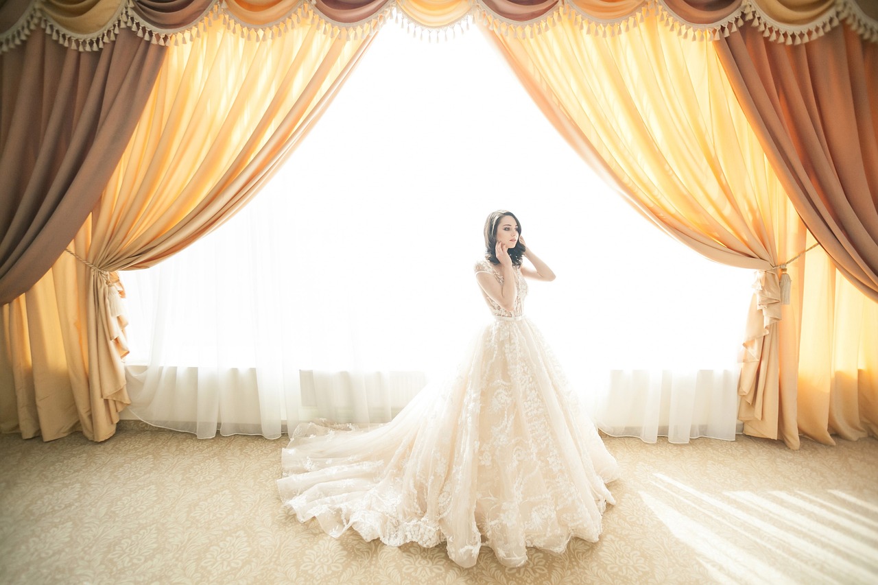 a woman in a wedding dress standing in front of a curtain, by Natasha Tan, pexels, baroque, long luxurious gown, 💣 💥, cream - colored room, airy colors