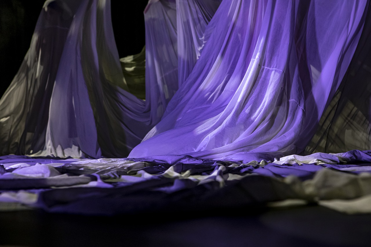 a group of purple cloths sitting on top of a floor, a picture, conceptual art, beautiful flowing fabric, backside of scenography elements, close up to the screen, dress in voile