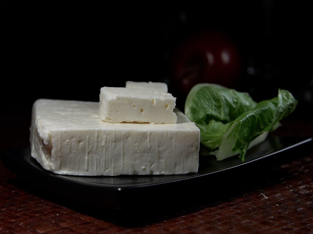 a black plate topped with tofu and lettuce, a picture, by Adam Chmielowski, pixabay, bauhaus, butter sculpture, ivory skin, greek, shot on kodak vision 200t