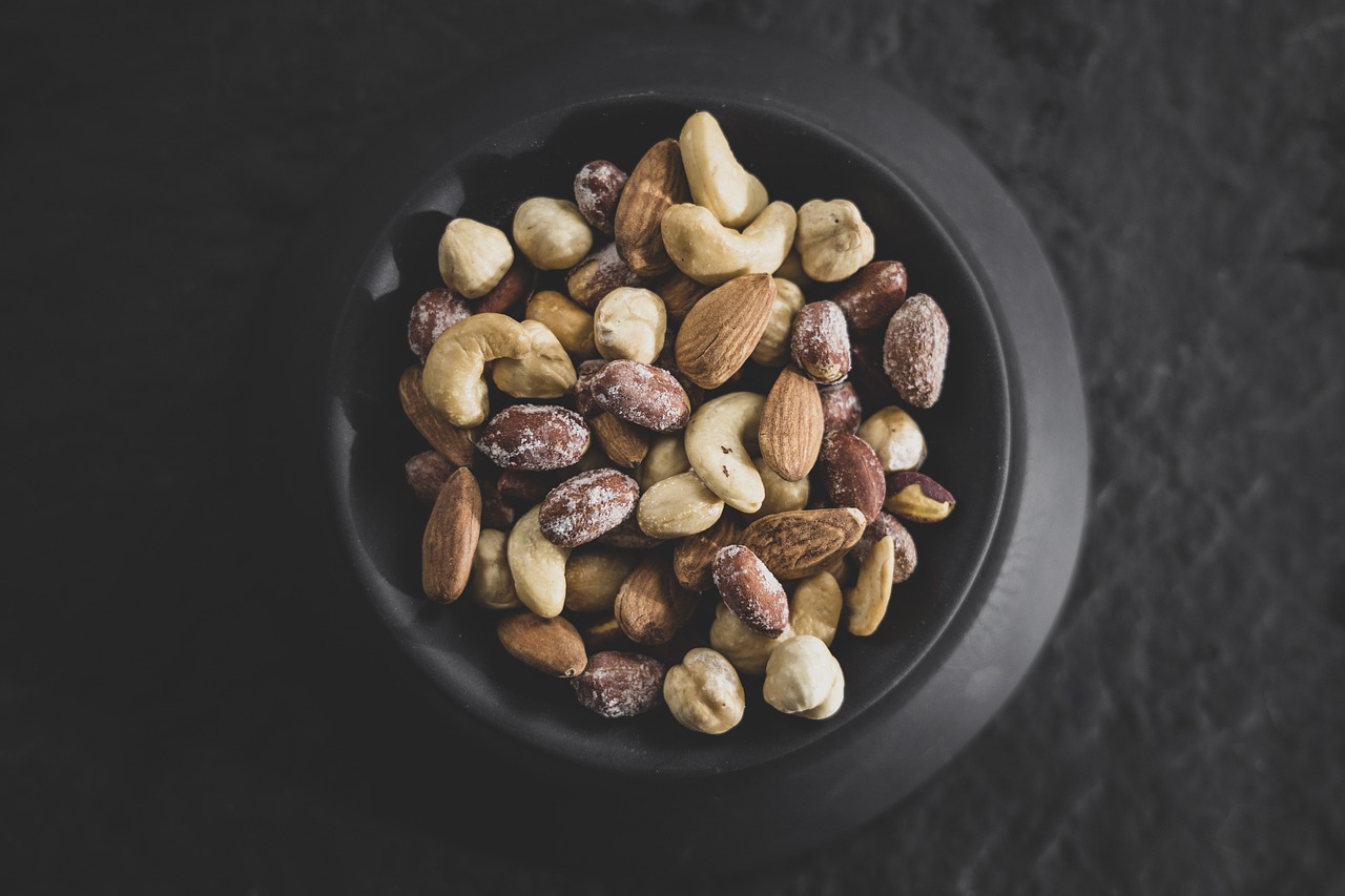 a bowl filled with nuts on top of a table, by Jan Kupecký, pexels, on a dark rock background, high detail product photo, 🦩🪐🐞👩🏻🦳, bottom angle