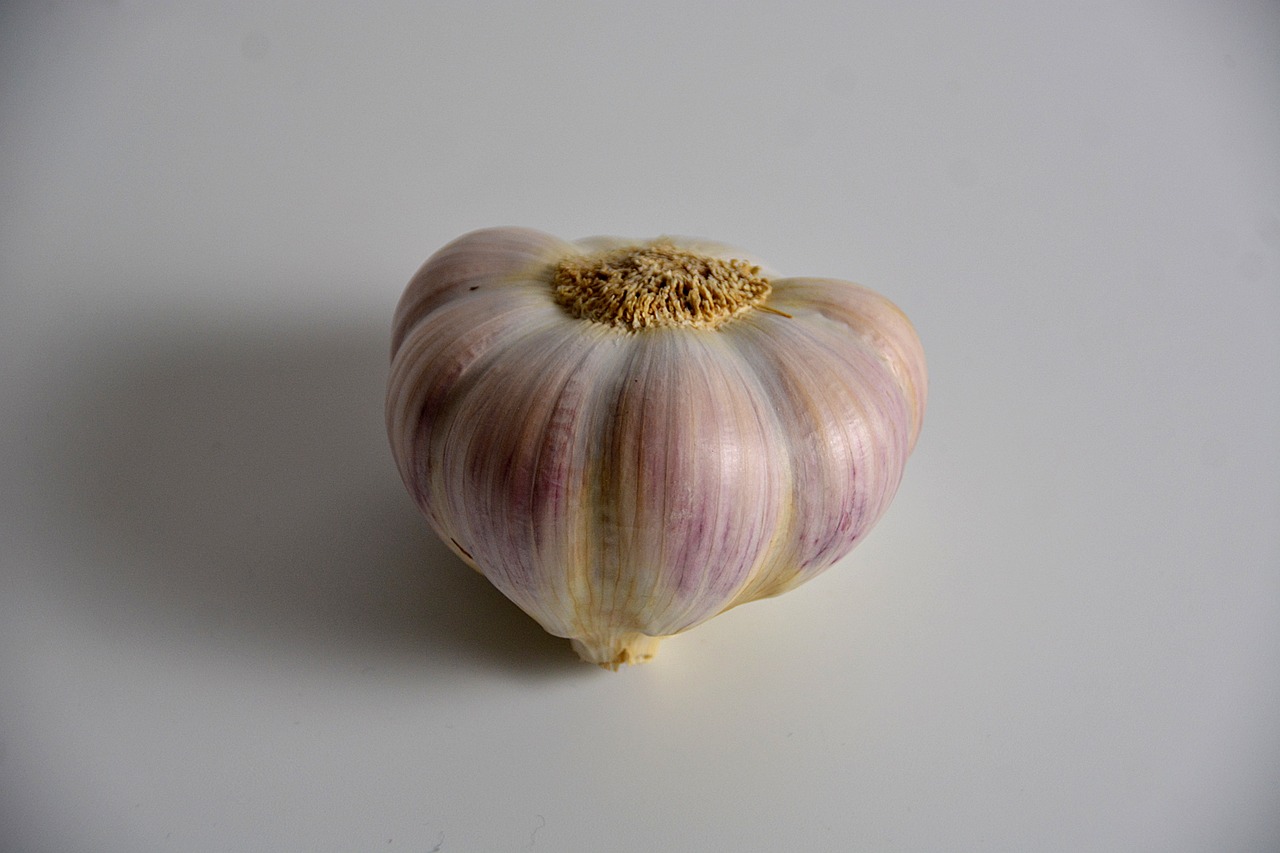 a close up of a bulb of garlic on a table, a macro photograph, pixabay, hurufiyya, with a white background, (heart), extremely pale blond hair, view from bottom to top