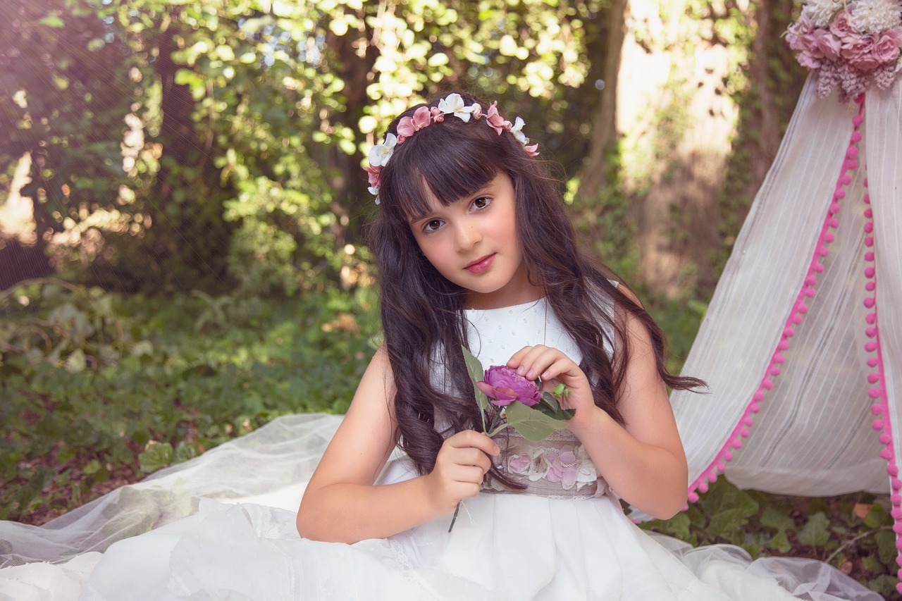 a little girl sitting on the ground with a flower in her hand, a picture, inspired by Sophie Gengembre Anderson, brunette elf with fairy wings, breathtaking flower tiara, photoshoot portrait, alanis guillen