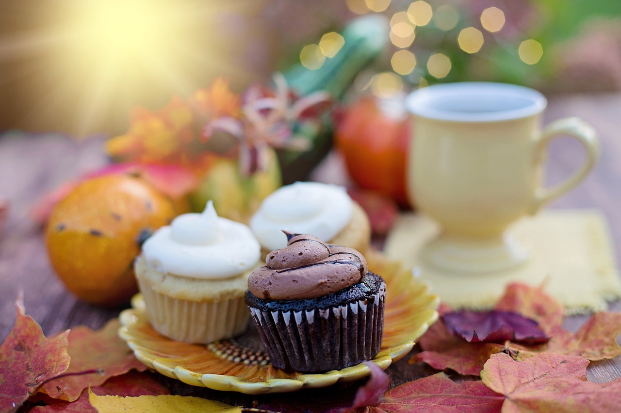 a plate topped with cupcakes next to a cup of coffee, a photo, by Tom Carapic, shutterstock, autum garden, very shallow depth of field, stock photo, autumn sunlights