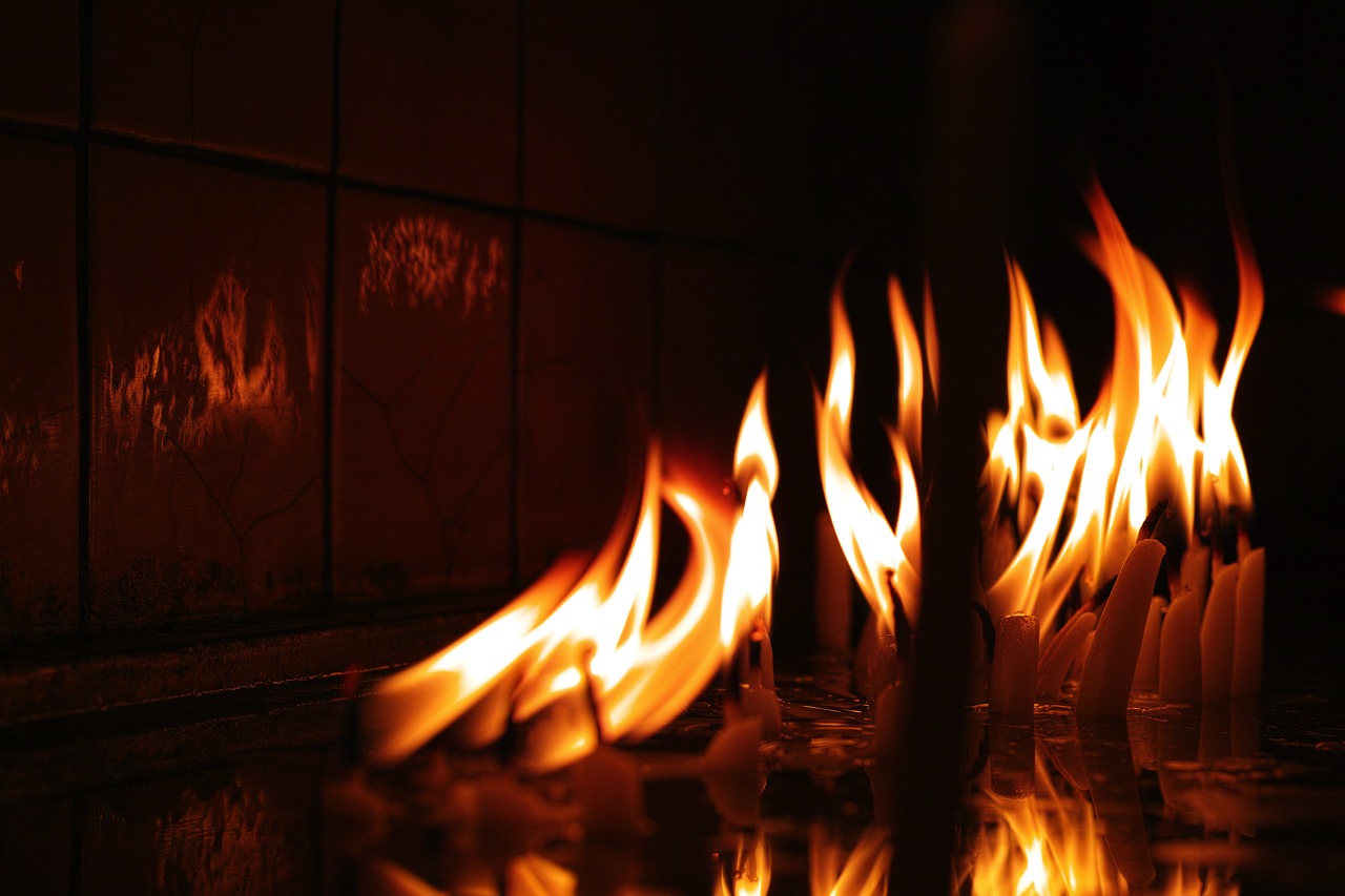 a bunch of candles that are on a table, hurufiyya, fire place roaring, wearing tumultus flames, discovered photo, fire reflection