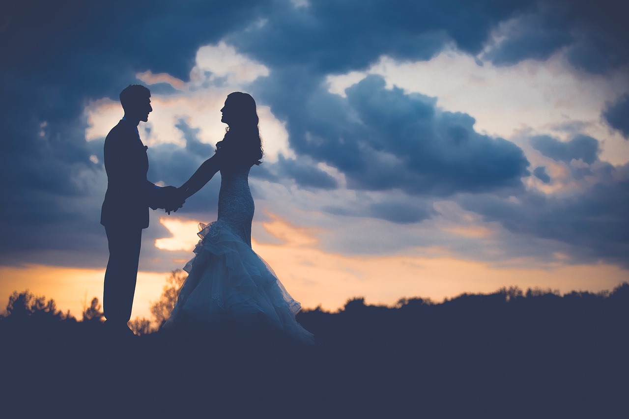 a bride and groom holding hands at sunset, a picture, shutterstock, romanticism, sunset and big clouds behind her, dimly lit scene, wearing a magnificent dress, dlsr photo