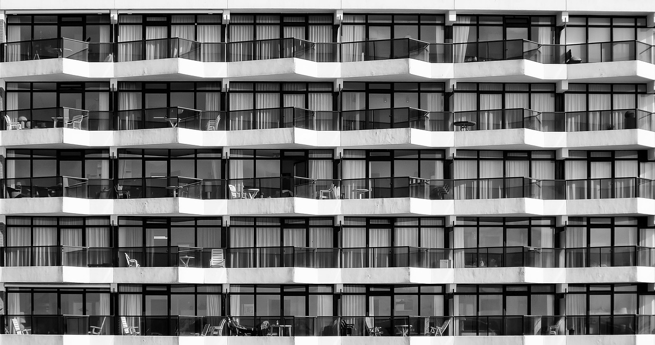 a black and white photo of a tall building, a black and white photo, inspired by Ned M. Seidler, unsplash, brutalism, balcony scene, repetition, hotel room, near the sea