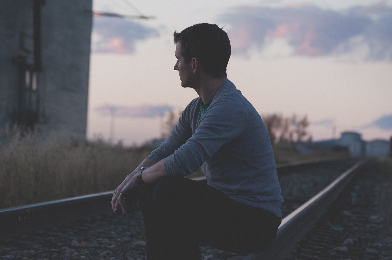 a man sitting on top of a train track, by Matt Cavotta, peaceful mood, side profile, tyler west, unhappy