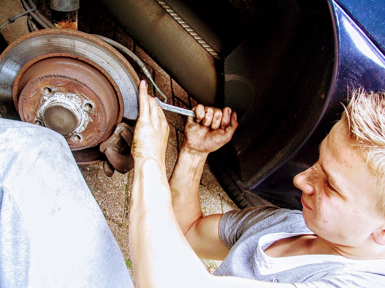 a man working on a tire with a wren, by John Luke, pexels, auto-destructive art, [ [ hyperrealistic ] ], underbody, screwdriver, ((oversaturated))