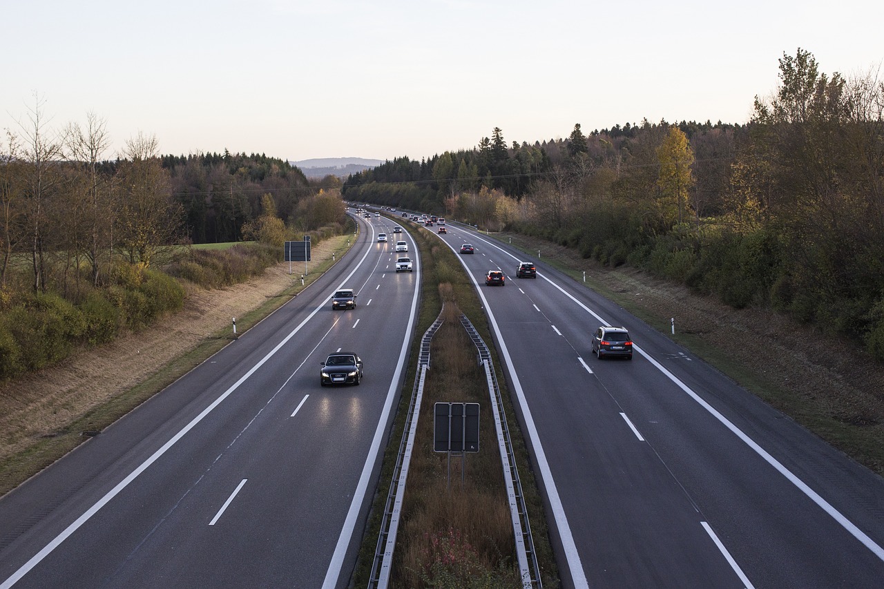 a highway filled with lots of traffic next to a forest, a picture, by Thomas Häfner, shutterstock, maintenance photo, lower saxony, concrete, plain stretching into distance