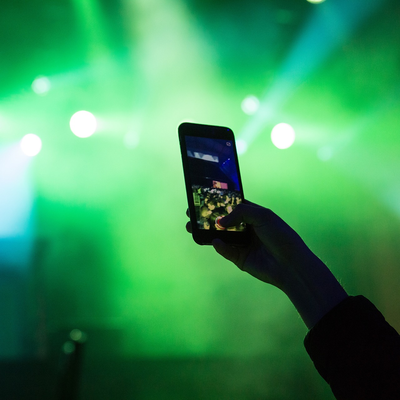 a person holding up a cell phone in front of a stage, a picture, by Anato Finnstark, shutterstock, green scary lights, pov photo, stock photo