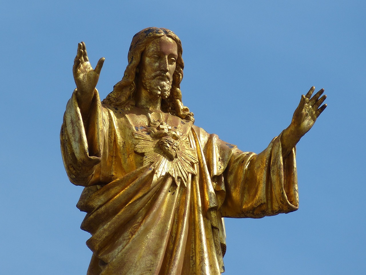 a golden statue of jesus on top of a building, a statue, by Andrei Kolkoutine, pexels, art nouveau, closeup of arms, catholic icon, black jesus, very very well detailed image