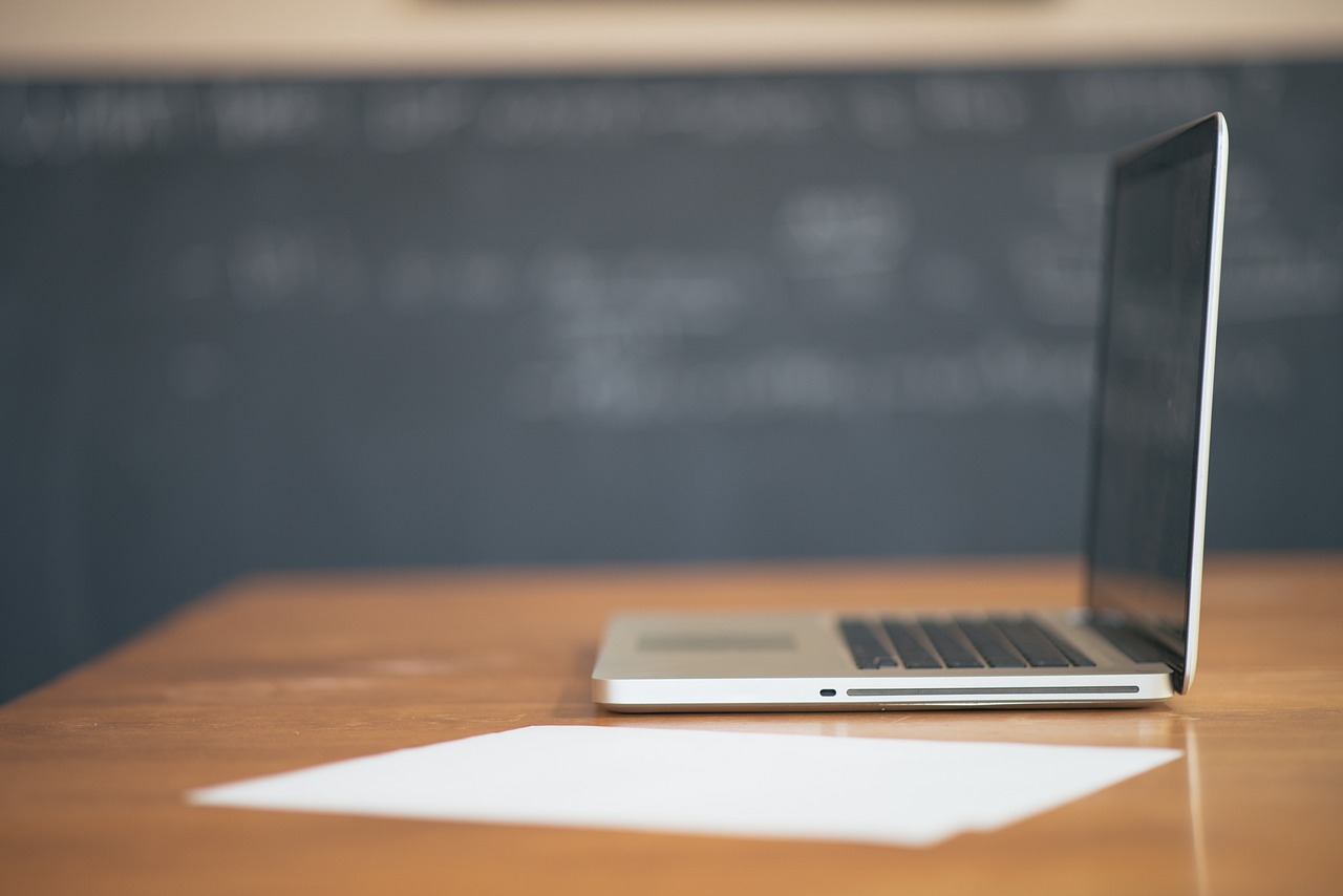 a laptop computer sitting on top of a wooden desk, shutterstock, classroom background, black chalk, document photo, mid shot photo