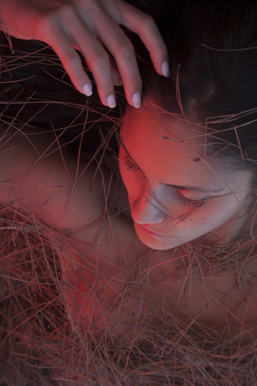 a woman laying on top of a pile of dry grass, cgsociety contest winner, digital art, volumetric lighting. red, high angle closeup portrait, wires for hair, photorealistic ”
