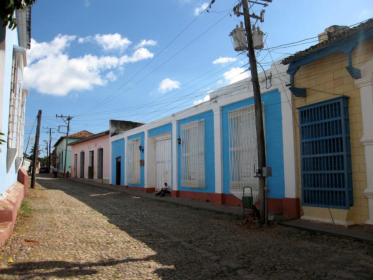 a cobblestone street lined with colorful buildings, by Ceferí Olivé, flickr, dada, cuba, pale blue, several cottages, gloss