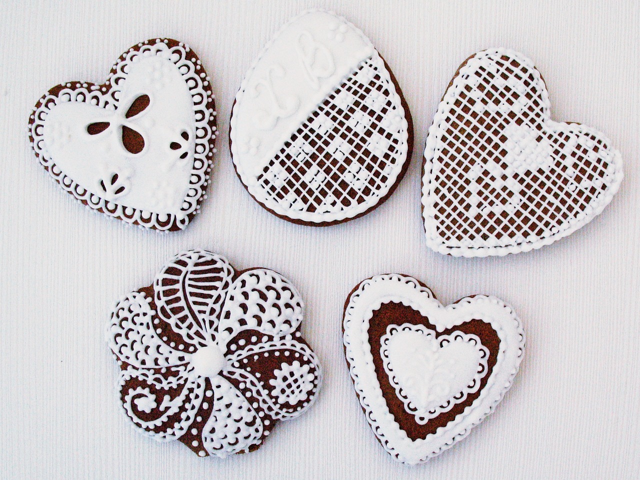 a group of heart shaped cookies sitting on top of a table, a picture, inspired by Dóra Keresztes, folk art, intricate and detailed lace set, 3 4 5 3 1, white details, chocolate