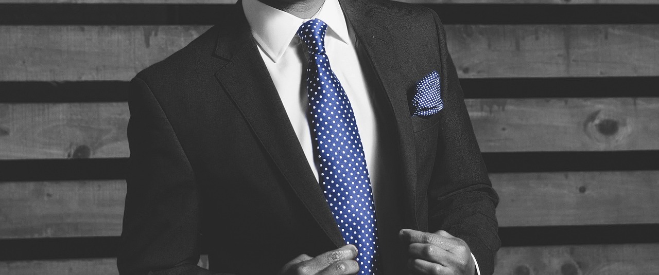 a black and white photo of a man in a suit and tie, a stock photo, pexels, costume with blue accents, polkadots, realistic image, dressed with expensive clothes