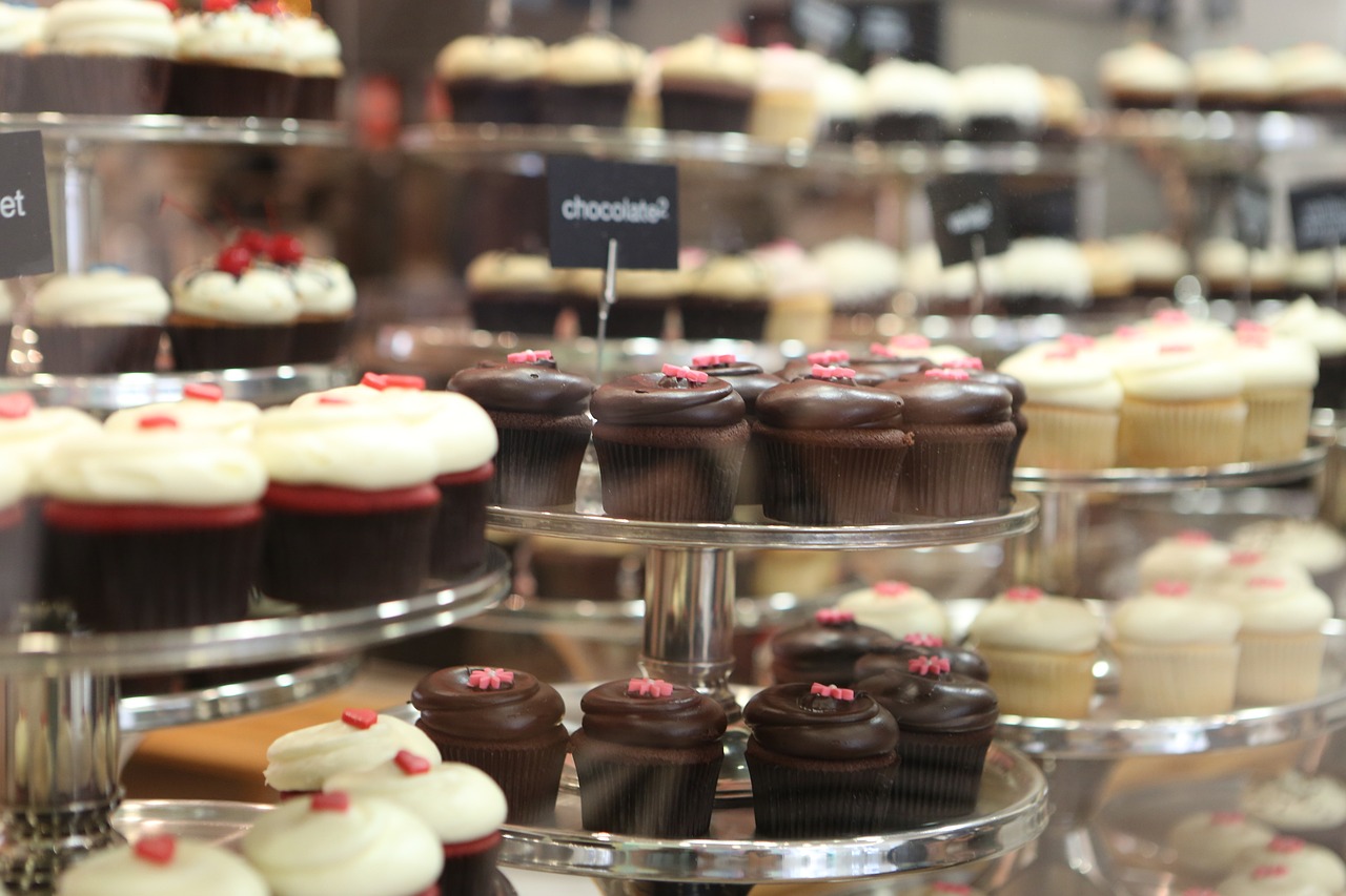 a display case filled with lots of different types of cupcakes, figuration libre, high res photo, 35 mm product photo”