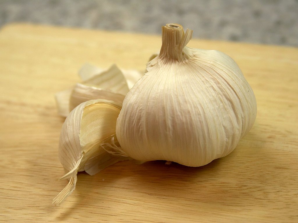 a close up of a clove of garlic on a cutting board, a picture, by Alexander Scott, wikimedia, extremely pale blond hair, kodak photo, computer - generated