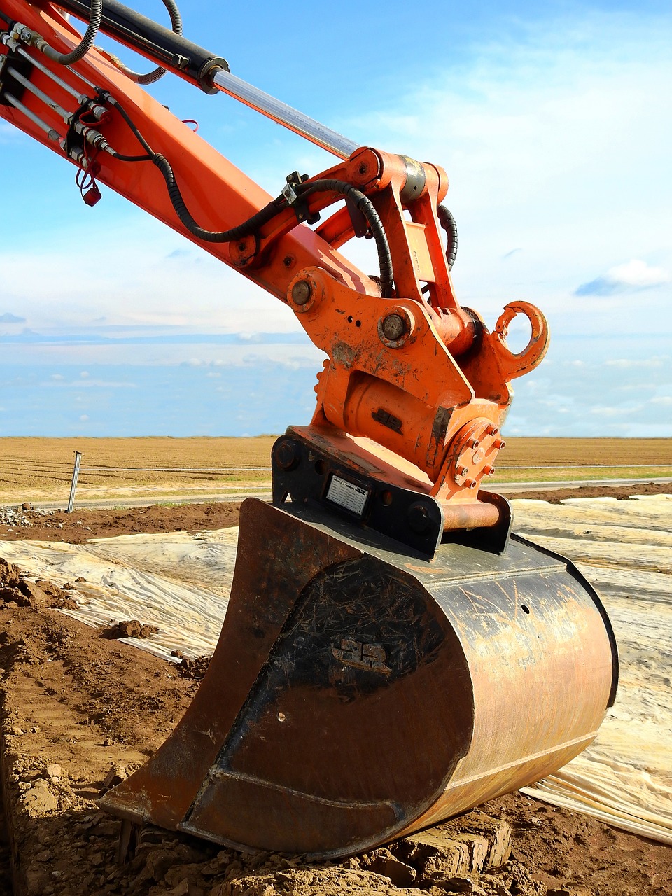 a large orange excavator sitting on top of a pile of dirt, shutterstock, looking towards the horizon, close up image, tools, installation