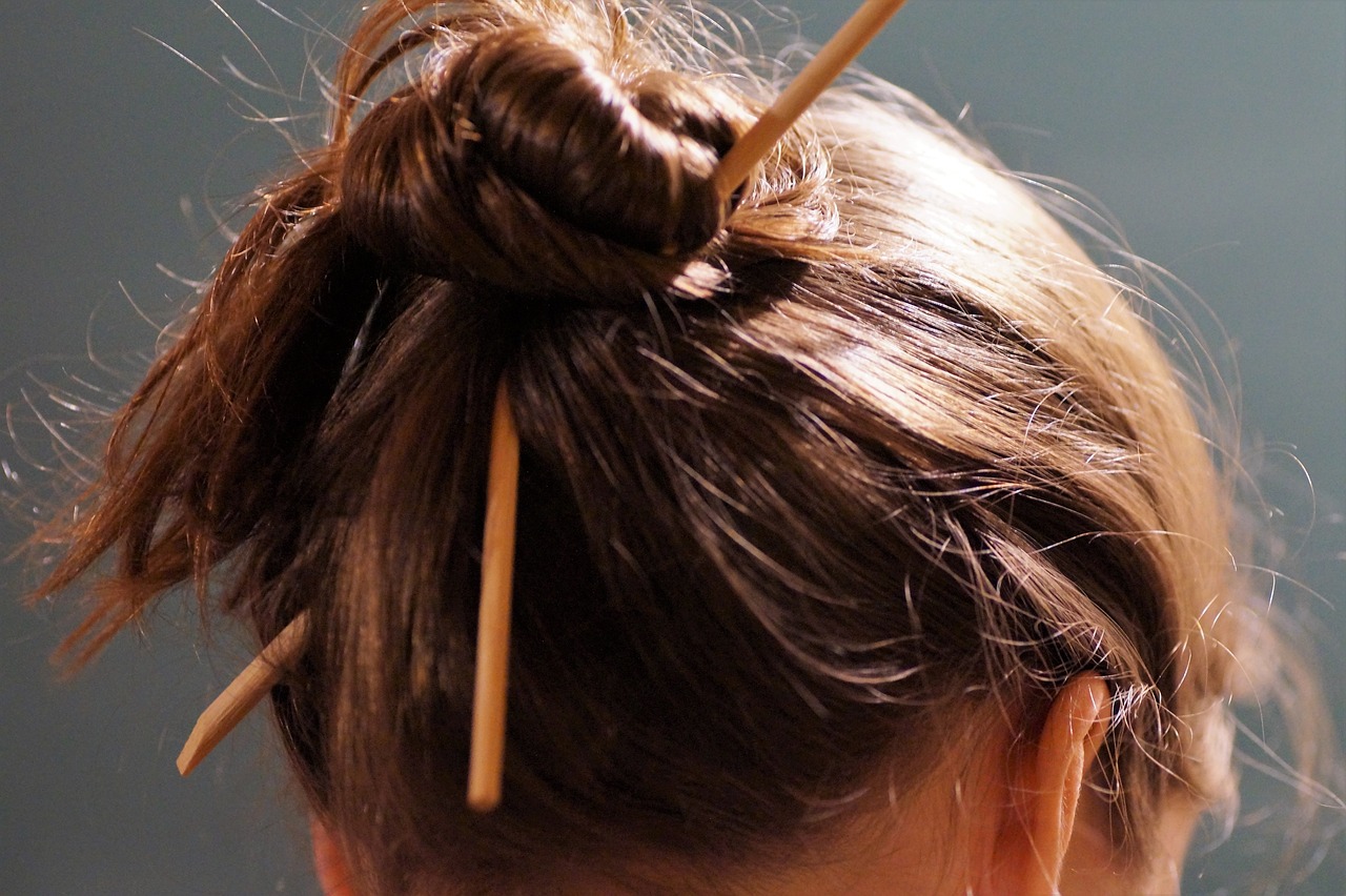 a woman with a pair of toothpicks in her hair, inspired by Shūbun Tenshō, unsplash, round-cropped, 4 k detail, 2 1 st century, chopsticks