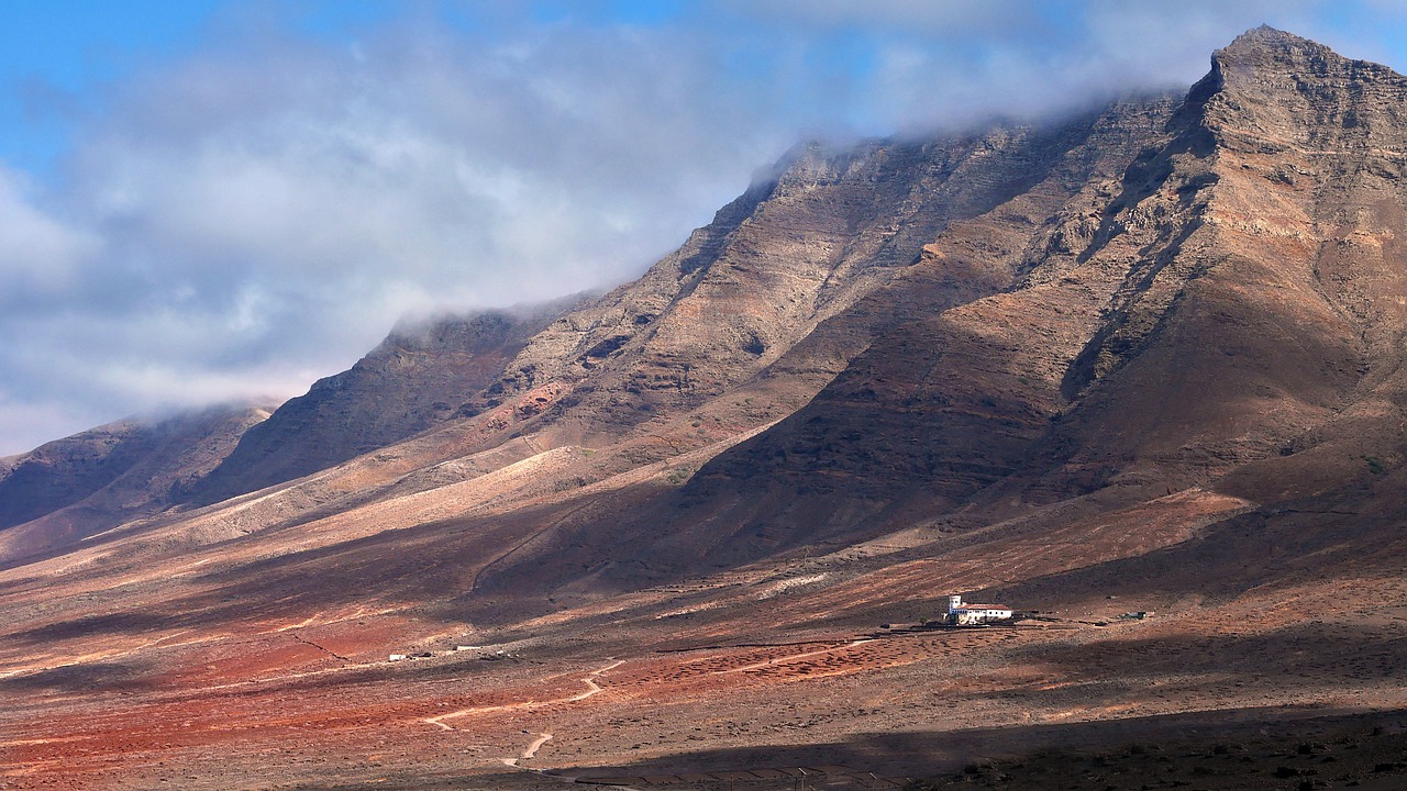 a large mountain with a small house in the middle of it, by January Suchodolski, flickr, les nabis, red sand, big island, high elevation, monastery