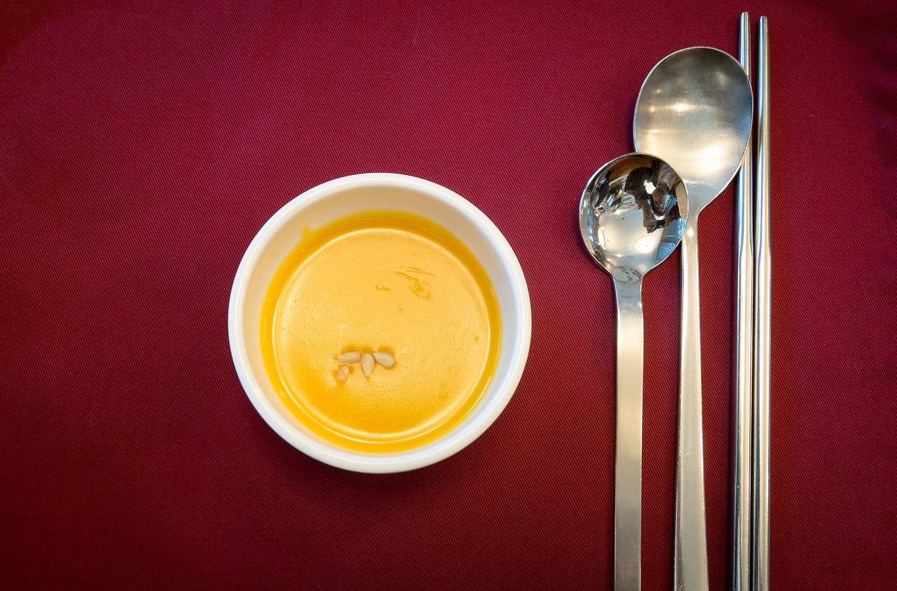 a bowl of soup and two spoons on a table, by Jan Rustem, flickr, pumpkin, fine dining, mustard, trio
