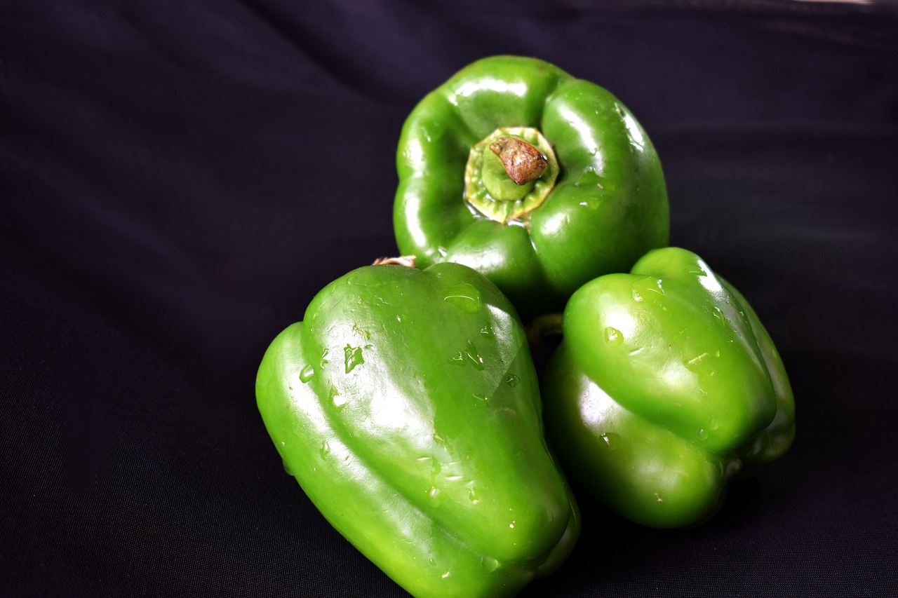 a group of green peppers sitting on top of a black surface, renaissance, studio portrait photo, close-up product photo, rain lit, very sharp photo