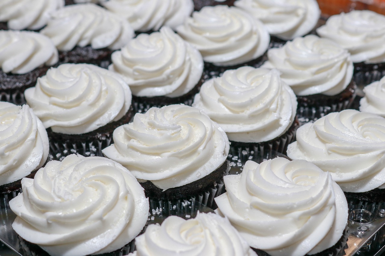 a close up of a tray of cupcakes with frosting, a photo, by Kathleen Scott, detailed white, sigma 1.6, interesting angle, whirling