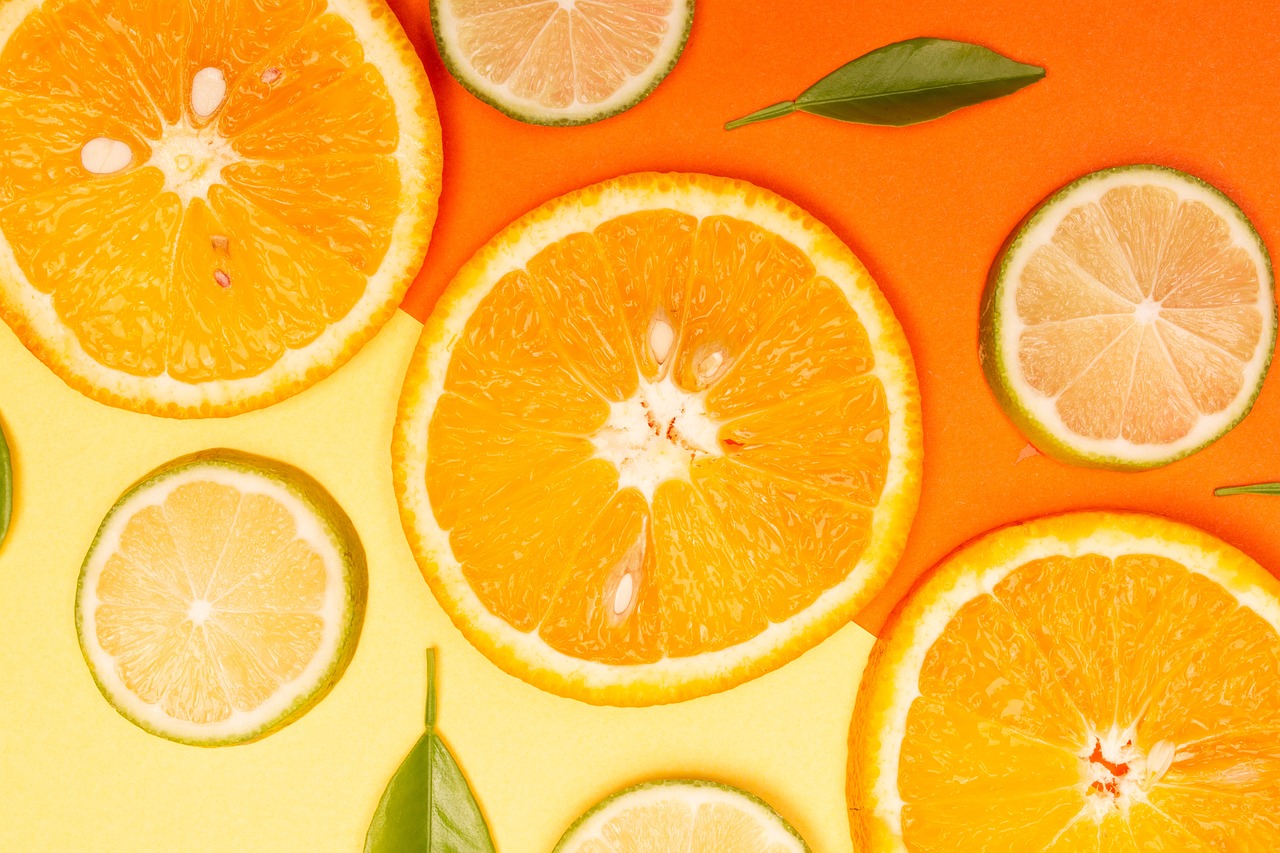 a group of sliced oranges sitting on top of a table, by John Luke, trending on pexels, process art, green and yellow colors, vibrant orange background, background image, lemonade