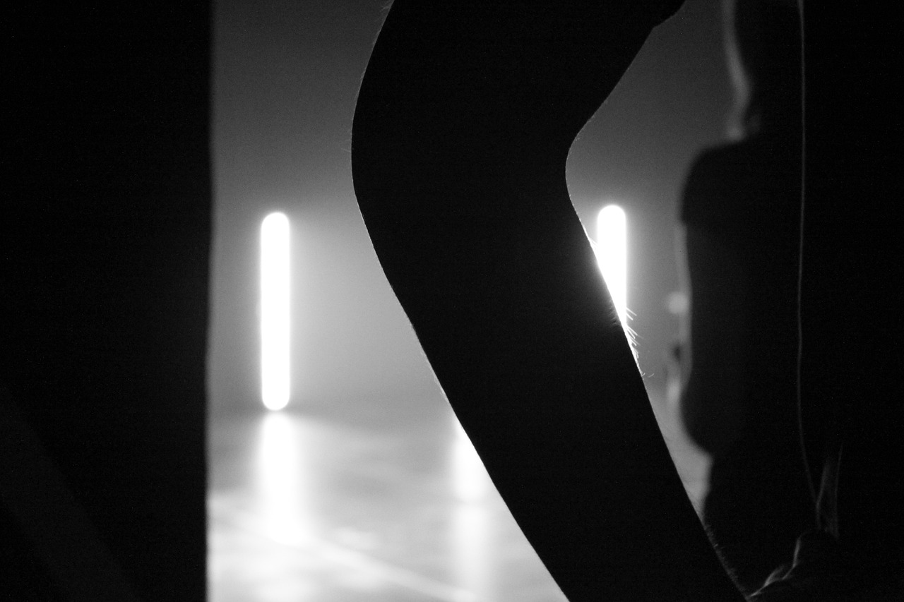 a black and white photo of a person in the dark, light and space, closeup of arms, modern dance aesthetic, backlit glow, about to step on you