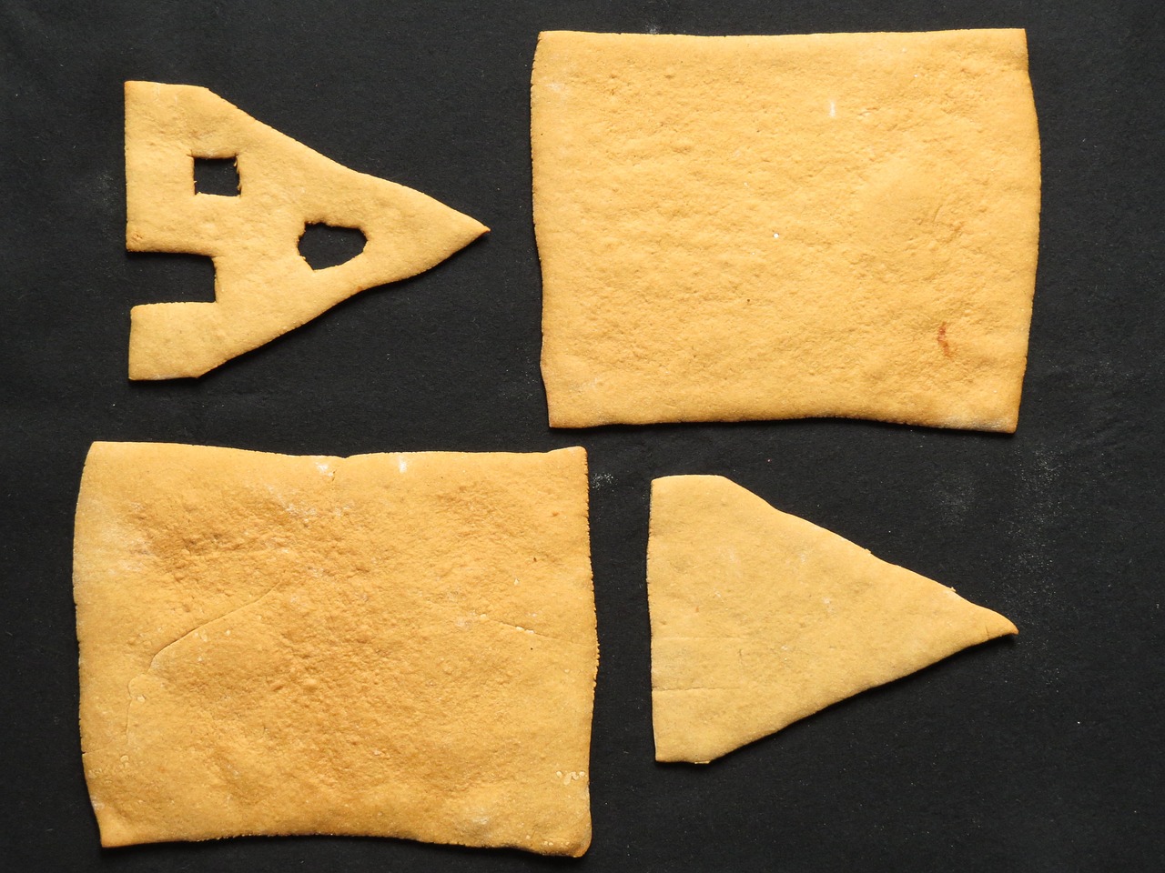 a couple of pieces of bread sitting on top of a table, inspired by Antoni Tàpies, folk art, houses, on a black background, view from bottom to top, little windows