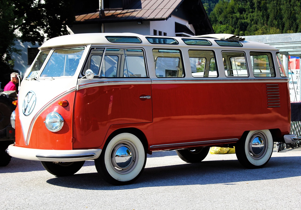 a red and white vw bus parked in front of a building, by Dennis Ashbaugh, pixabay, retrofuturism, stained antique copper car paint, with a roof rack, extremely polished, view from the side”