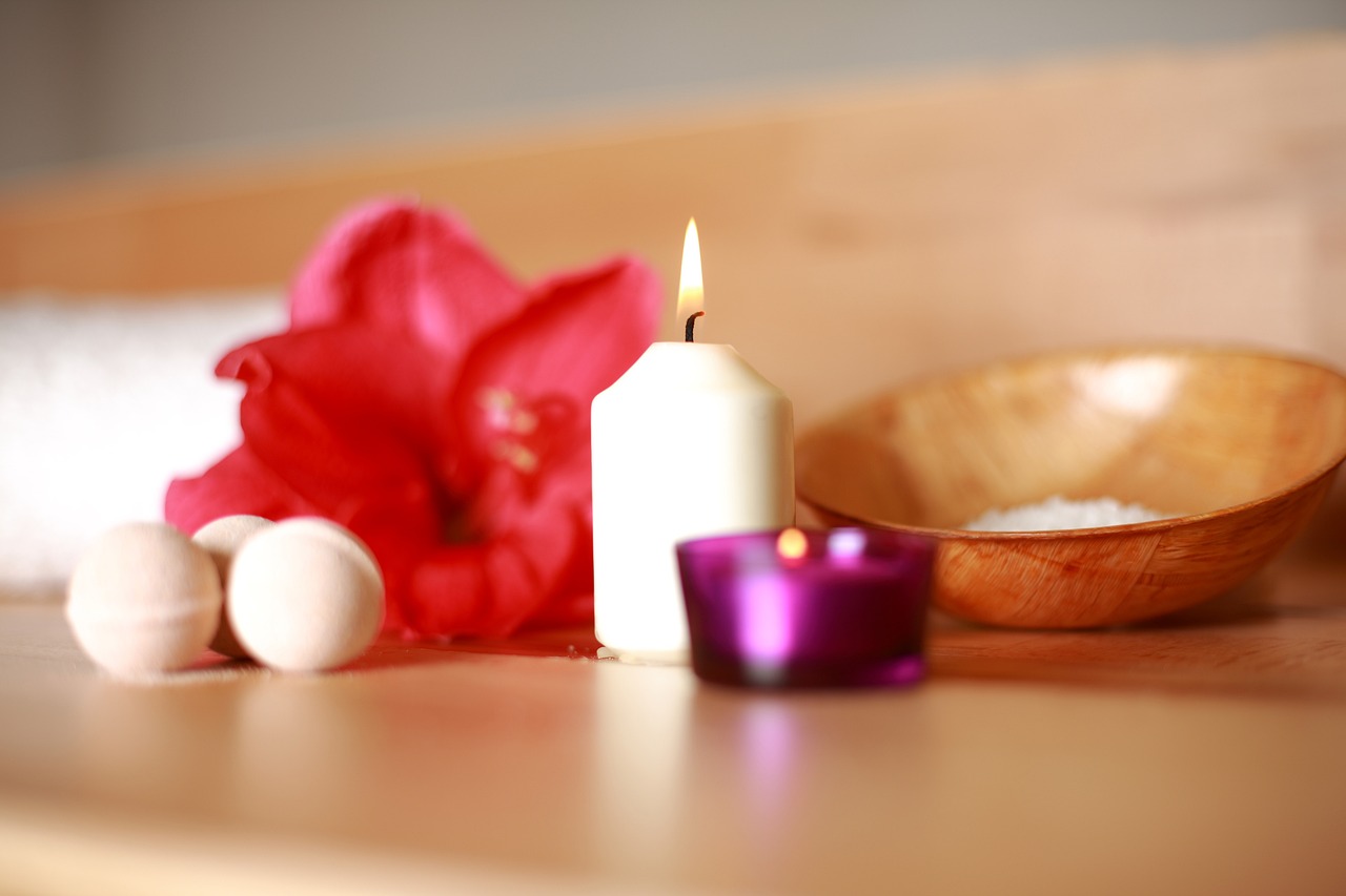 a candle sitting on top of a table next to a bowl of eggs, a still life, by Rhea Carmi, pexels, paradise garden massage, white and red color scheme, flower, shallow dof