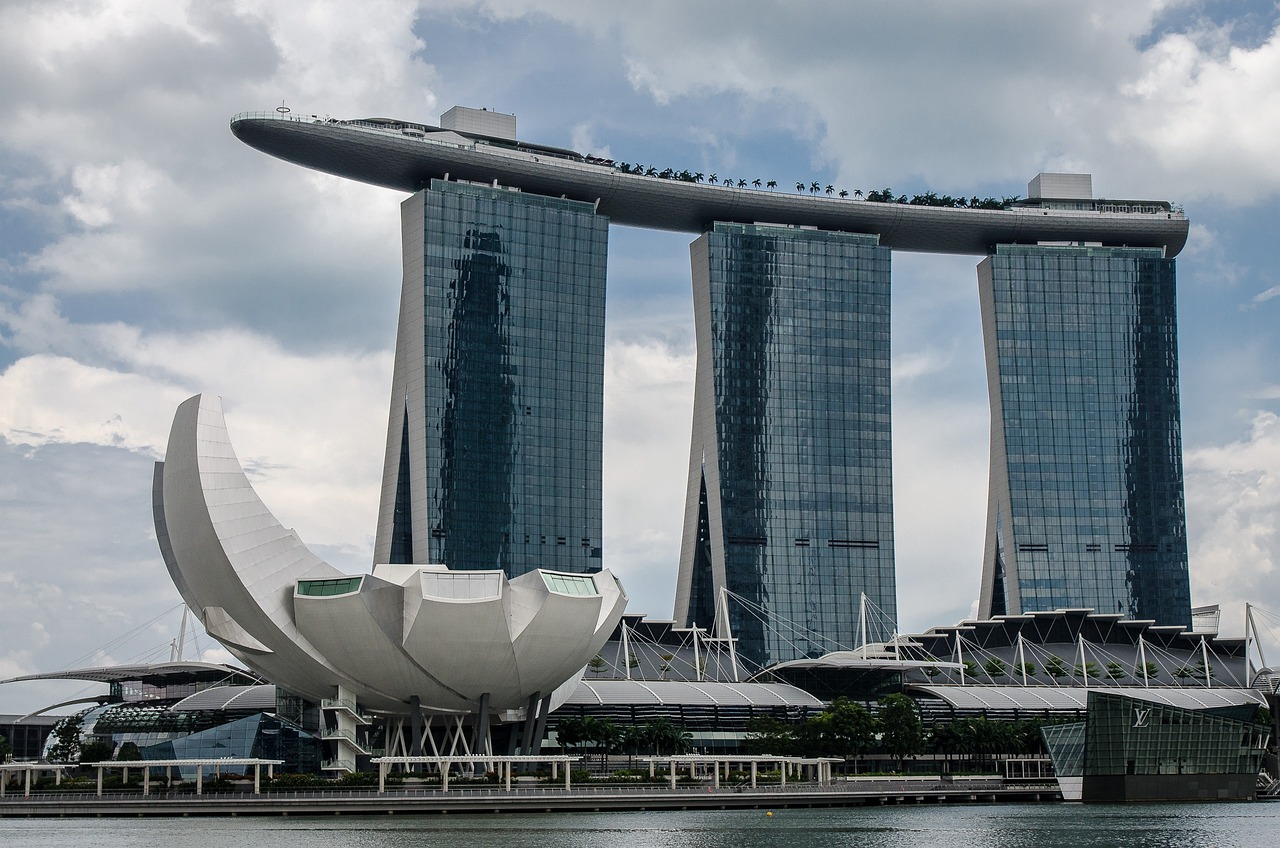 a large building next to a body of water, inspired by Zha Shibiao, pixabay, set on singaporean aesthetic, in style of norman foster, wikimedia, poppy