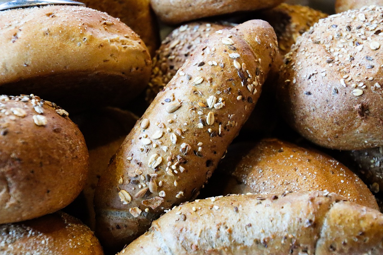 a pile of bagels sitting on top of a table, by David Garner, pexels, granular detail, baking french baguette, highly detailed closeup, seeds