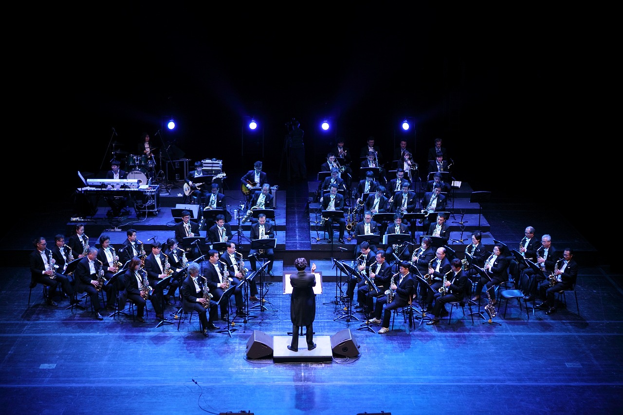 a man standing on top of a stage holding a microphone, by Jesús Mari Lazkano, pixabay, baroque, orchestra, taiwan, military, a wide shot