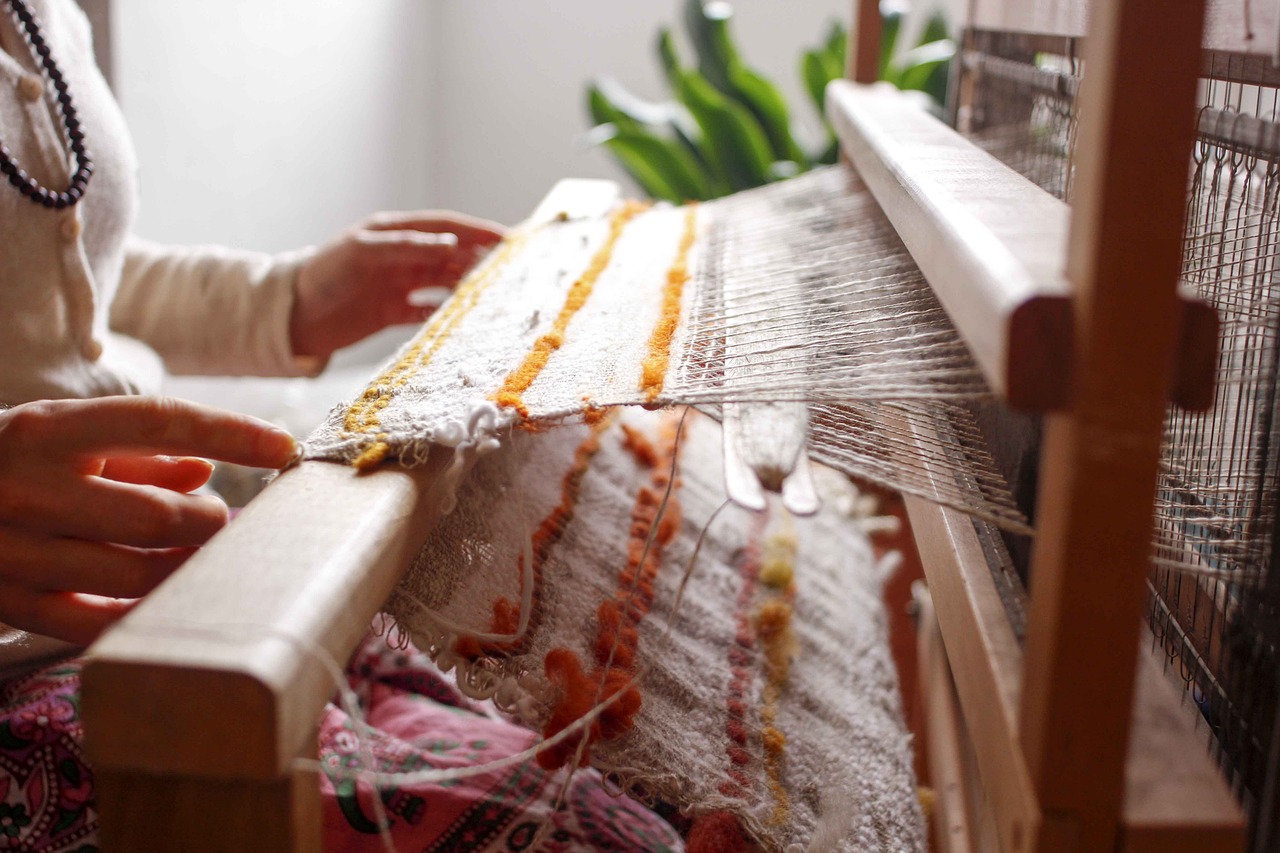 a woman weaving a piece of fabric on a loom, by Sylvia Wishart, trending on pexels, process art, 🦩🪐🐞👩🏻🦳, ocher details, natural and organic and flowing, light boho carpet