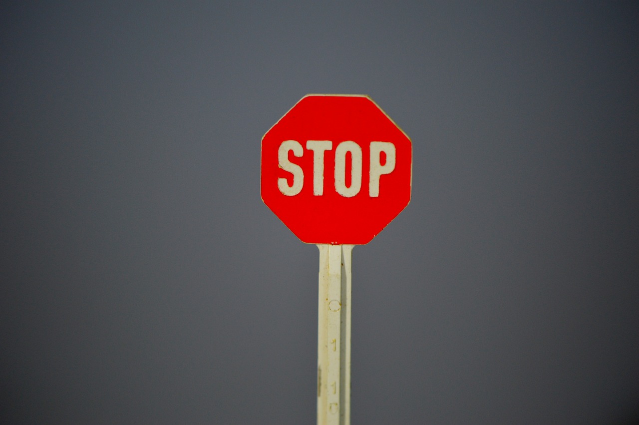 a red stop sign sitting on top of a wooden pole, by David Simpson, ivory, on a gray background, photo photo, sweet