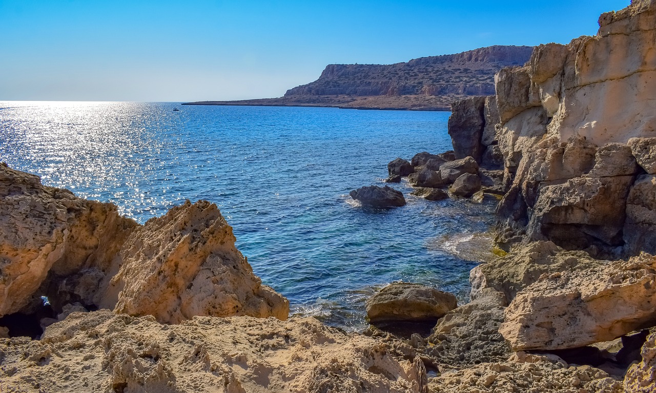 a large body of water surrounded by rocks, a photo, by Tom Wänerstrand, pixabay, cyprus, fan favorite, sharp cliffs, rocky desert