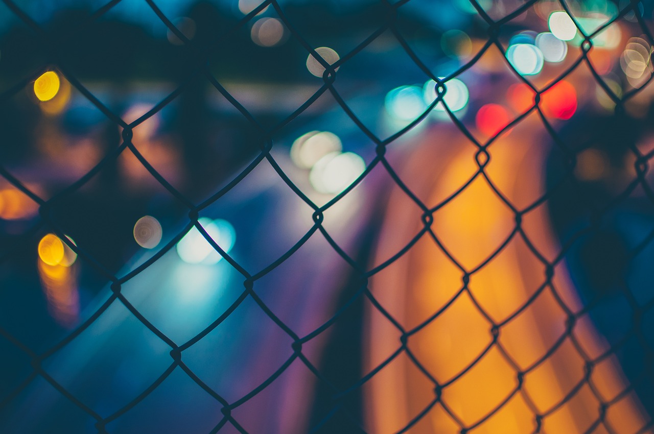 a view of a city at night through a chain link fence, pexels, colourful close up shot, instagram post, low resolution, torn mesh