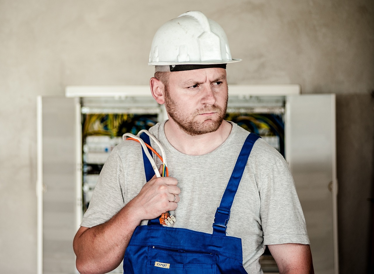 a man wearing a hard hat and overalls, apprehensive mood, cords and wires, mikko, beginner