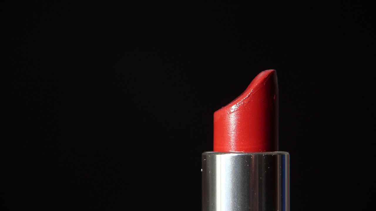 a close up of a red lipstick on a black background, by Jan Rustem, pixabay, photorealism, orange hue, shiny silver, professional product photo, sephora