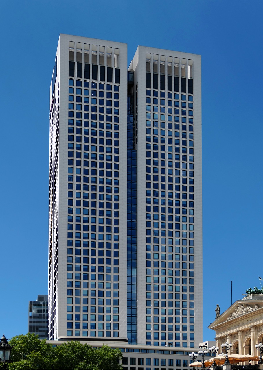 a couple of tall buildings sitting next to each other, capital plaza, blue sky, screens, three - quarter view