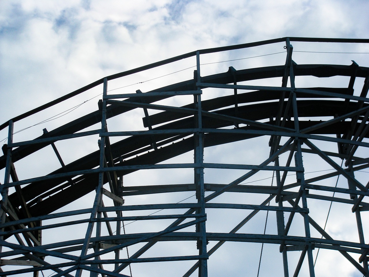 a roller coaster against a cloudy blue sky, by Edward Corbett, flickr, under repairs, detail, raven, rounded lines